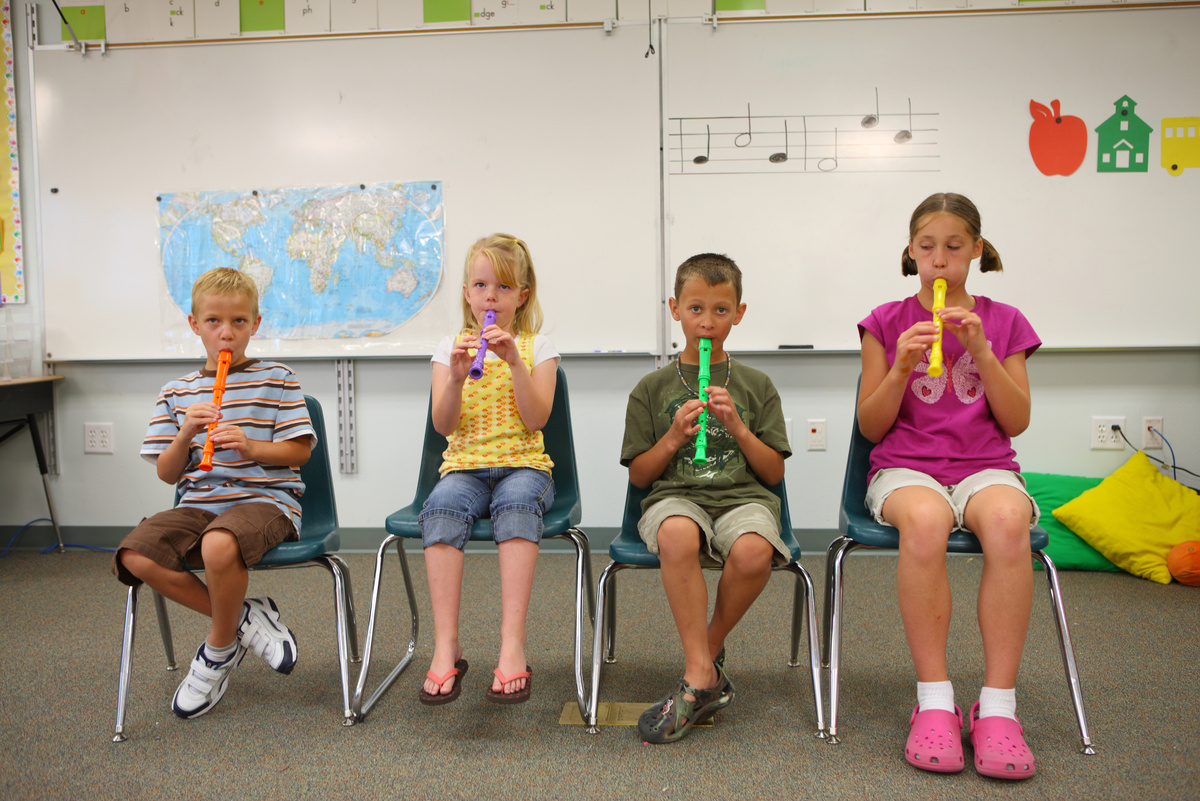 School age children playing colorful recorders in classroom